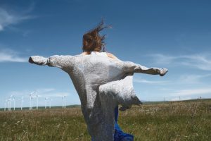 Woman with long tousled hair next to the wind turbine with the wind blowing