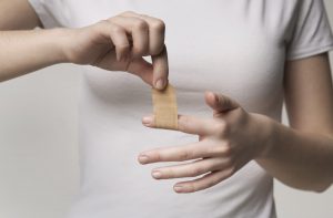 Woman using adhesive tape on injured finger