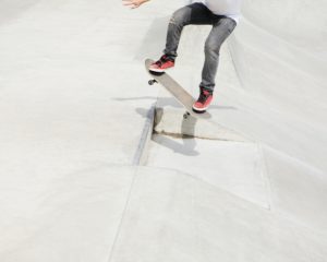 A teenage boy balancing on a skateboard in the city.