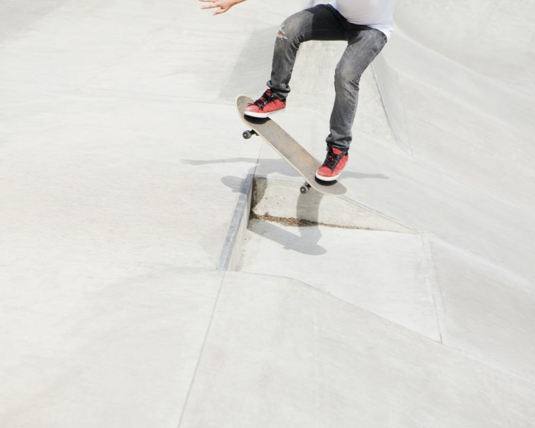 A teenage boy balancing on a skateboard in the city.