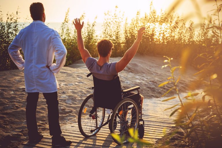 A man on wheelchair and his nurse.
