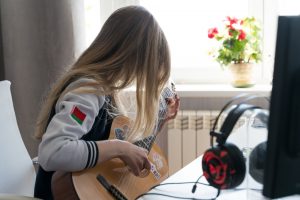 girl playing guitar in the room by the window